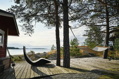 Puuterassi mäntyjen alla kalliorannalla, taustalla järvi.